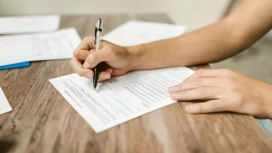 A close-up on the hand and forearm of a person filling in a paper questionnaire