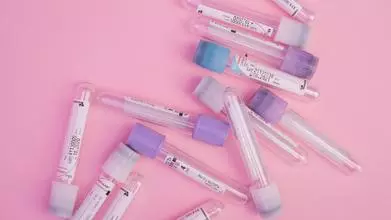 Set of blood test vials arranged on a pink table
