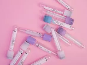 Set of blood test vials arranged on a pink table